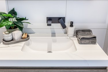 Closeup of modern white washbasin with black faucet