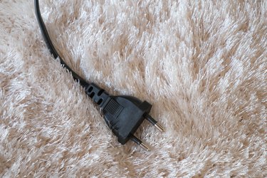 Electronic plug on white carpet texture