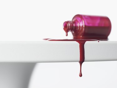 Nail polish dripping from white table.