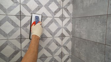 Black grout for tiles. laying ceramic tiles. Tilers fill the spaces between tiles with a rubber trowel. Grout in the bathroom.