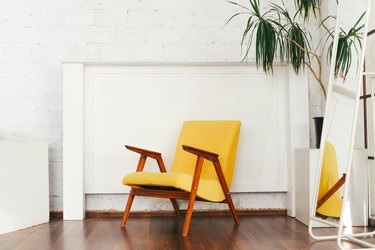 Yellow armchair and indoor plant against a white brick wall.