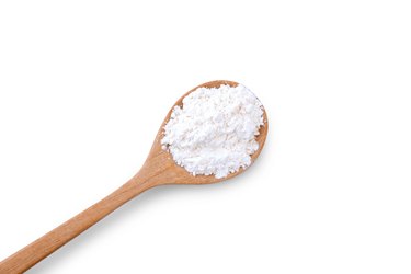 Calcium hydroxide powder (Deydrated lime) in wooden spoon isolated on white background.