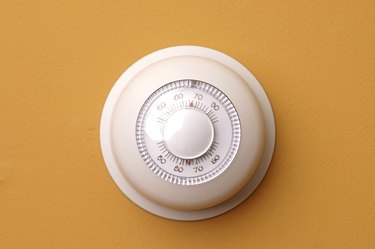 Closeup of a thermostat on a orange wall set to 68 degrees