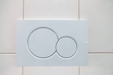 White dual buttons of flush toilet bowl in bathroom