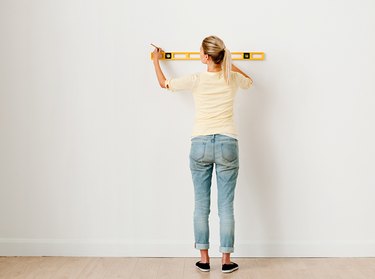 Woman using a spirit level on wall.