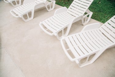White plastic lounge chairs next to pool.