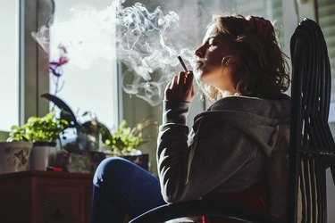Side View Of Woman Smoking A Cigarette At Home