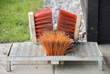 A modern boot scraper featuring orange bristle brushes attached to a silver metal plate.