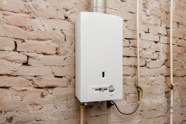 Closeup of gas water heater on a brick wall. Gas boiler in boiler room for hot water
