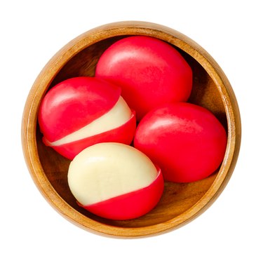 Snack cheese disks in red wax encasements, edam slices in wooden bowl