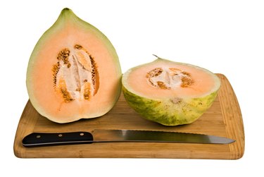 Crenshaw melon halves on cutting board with knife.