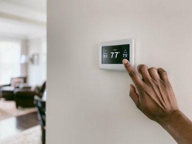 Woman adjusting touchscreen thermostat settings