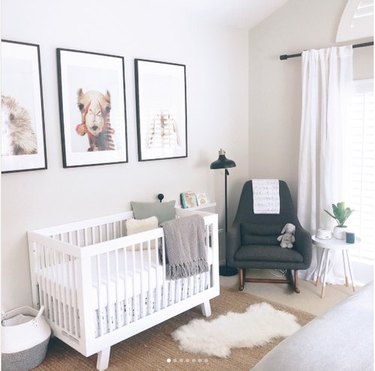 Gender-neutral nursery with three large photo prints of animal heads on wall: camel, hedgehog, and bunny; gray midcentury rocking chair, and white convertible crib