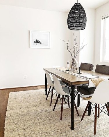 Minimal dining room with wooden rectangular table and white midcentury dining chairs. 