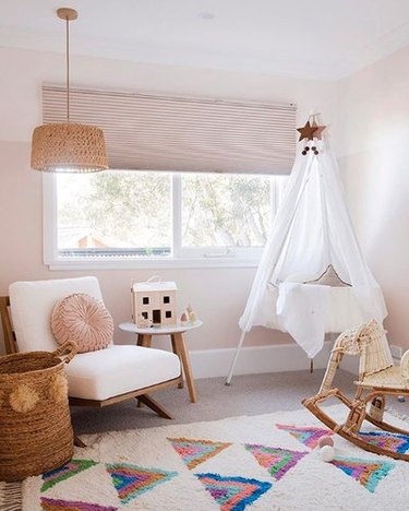 Neutral nursery with canopied bassinet and rattan elephant rocker