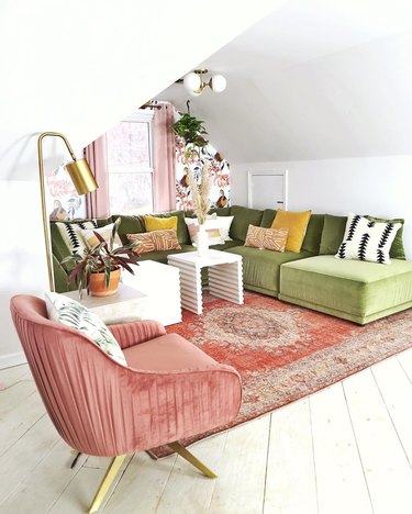 Retro attic design with olive velvet L-shaped couch and pink rug and wall mural