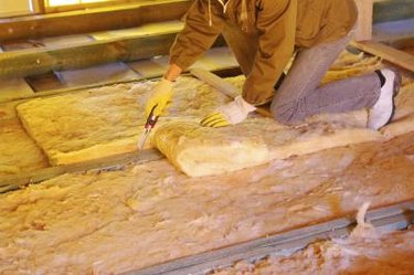 Construction worker thermally insulating house with mineral wool