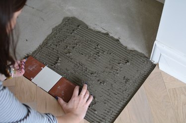 Placing red and white tiles into tile adhesive