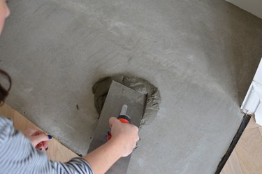 Trowelling tile adhesive onto concrete hearth