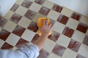 Sponging grout from checkered tiled hearth