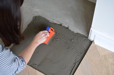 Combing floor tile adhesive to create ridges