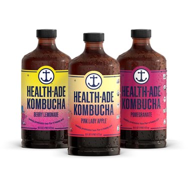 Three Health-Ade kombucha bottles in the pink lady apple, pomegranate, and berry lemonade flavors.