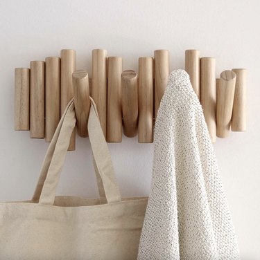 light pinewood peg coat rack against a white wall
