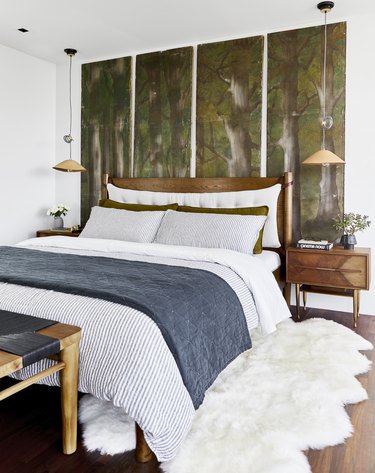 Bedroom with white bed, wooden furniture and green wall art