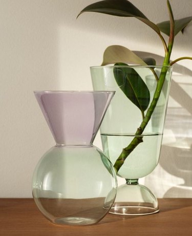 colored glass vase next to another colored glass item with a plant inside