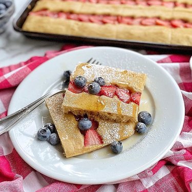 sheet pan pancakes with berries on white plate