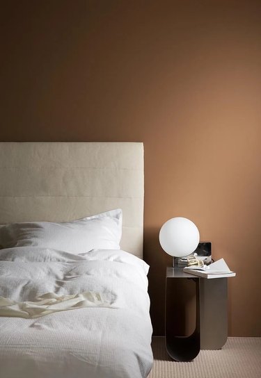Brown bedroom with white bed and globe light.
