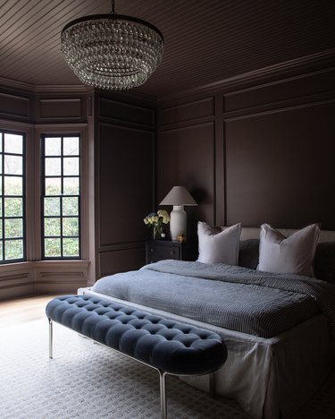 Dark brown bedroom with chandelier and light brown bedding