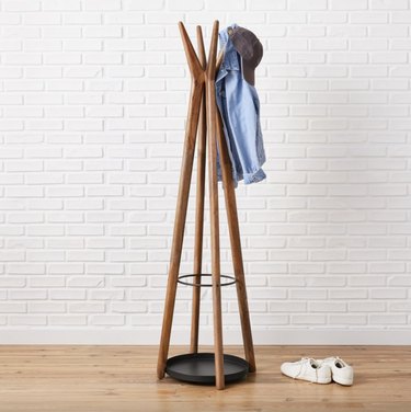 Light wood freestanding coat rack with a teepee design that has tapered hooks