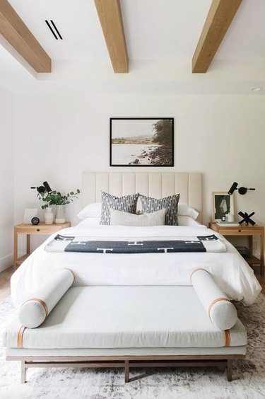 bedroom lighting idea with exposed ceiling beams and upholstered headboard