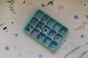 Pressed flower petals and lavender buds inside green silicone mold