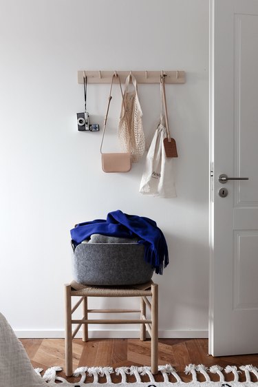 Detail of a closet with peg rail and chair with gray fabric basket.