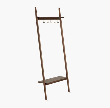 Leaning coat rack with ladder look. Six gold hooks across the top and a shelf at the bottom