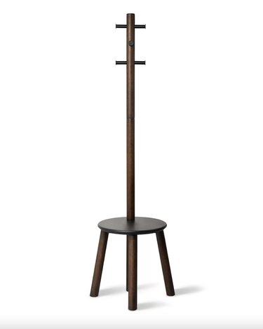freestanding coat rack in a dark wood with 6 pegs and a stool at the bottom