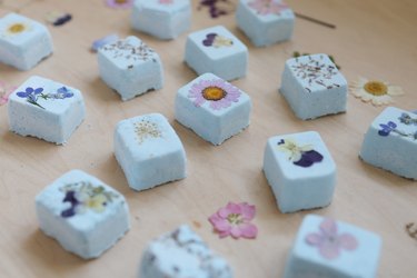 DIY Shower Steamers with pressed flowers on a wood surface