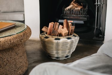 fireplace with couch and basket with wood nearby