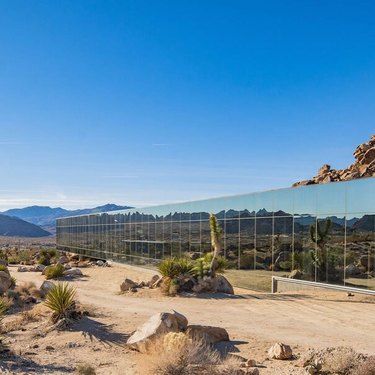 "Invisible House" in Joshua Tree, California, among the desert and in front of a blue sky.