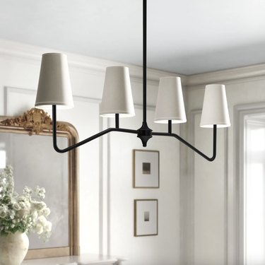 linear black chandelier with white shades in a living room.