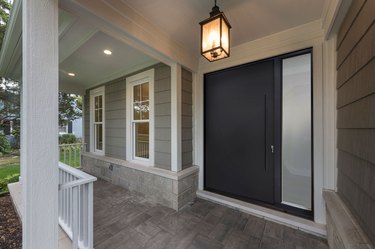 A black aluminum door with a sidelight and a covered porch