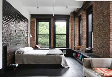 loft bedroom with exposed brick and black floors