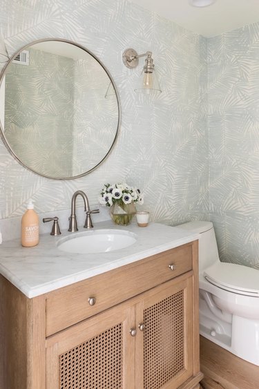 A bathroom with light tropical wallpaper