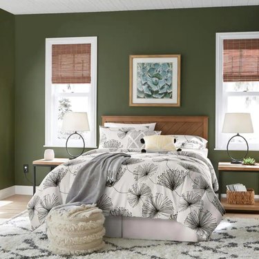 StyleWell Fergus Patina Finish Bed with leaf-printed duvet cover sits in room with green paint on walls.