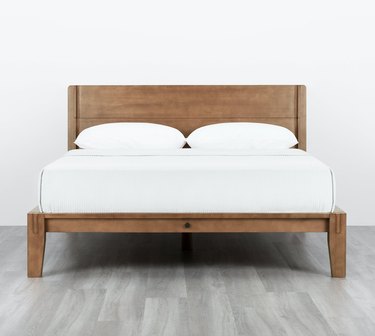 Thuma The Bed in Walnut with white sheet and pillows.