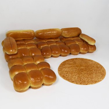 a couch design made of bread with a rug nearby also resembling bread