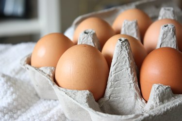 A zoomed in image of a carton of eggs with one missing in the front.