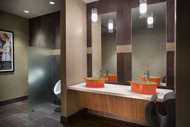 bathroom with two mirrors and bright orange sinks that are Le Creuset pots